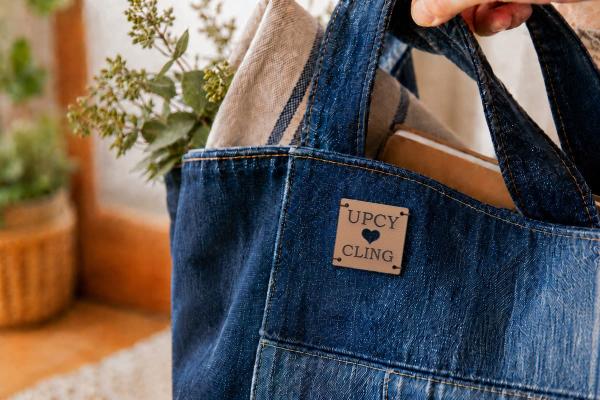 Étiquette carrée marron clair en cuir de cactus, « UPCYCLING » et cœur découpé, sur sac en jean.