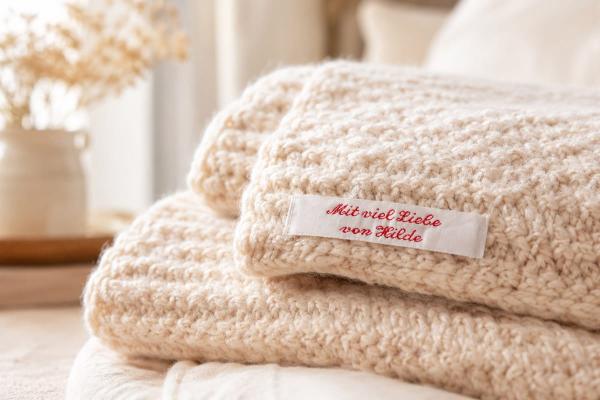 Étiquette en coton blanche avec texte rouge sur couverture tricotée