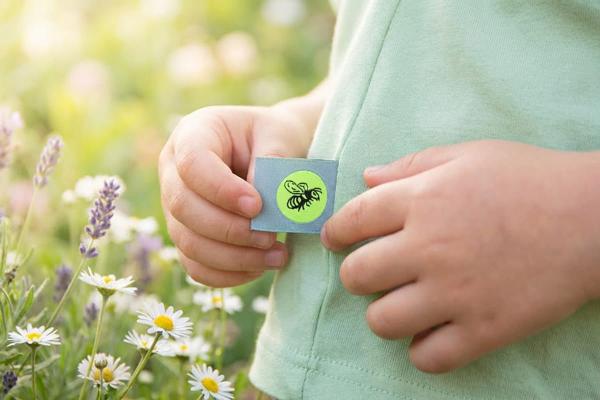 Étiquette bleu clair avec abeille cousue dans la couture d’un vêtement enfant